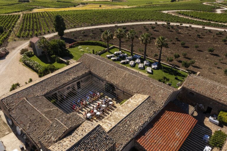 The baglio from the air: the courtyard laid for lunch, the palms, the vineyards behind, My Sicily Wedding