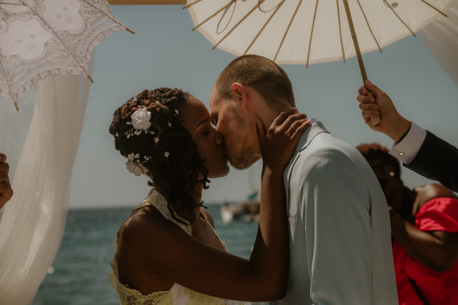 A bride and groom kiss beneath a white pavilion