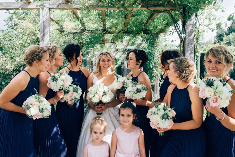 Bridesmaids and flower girls in navy and blush, garden pergola behind, Nadine Pyke Make Up Artist