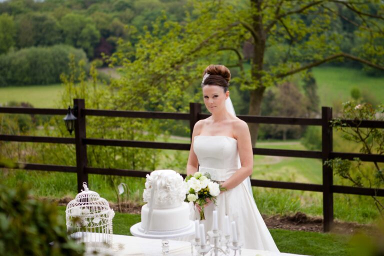 A bride beside a styled reception table, birdcage and wedding cake behind her, Nadine Pyke Make Up Artist
