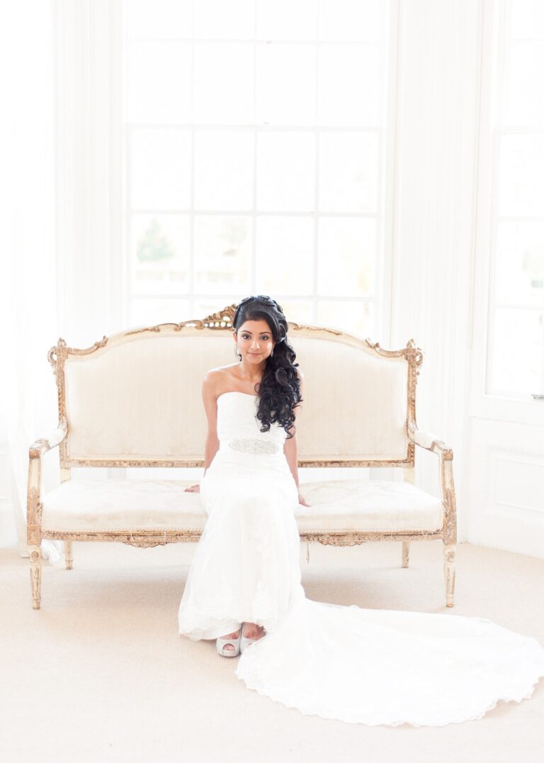 A bride seated on a gilt vintage sofa, fitted lace gown, Nadine Pyke Make Up Artist