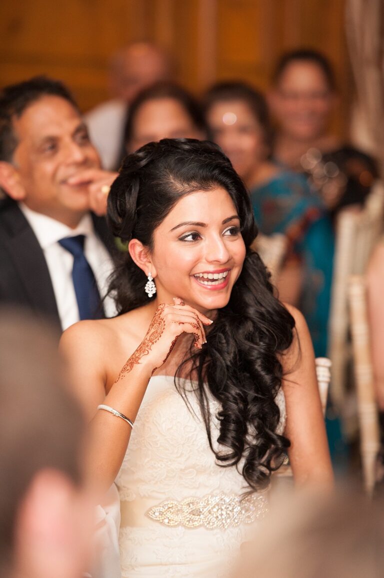 A bride laughing among her guests, loose curls and bridal henna visible, Nadine Pyke Make Up Artist