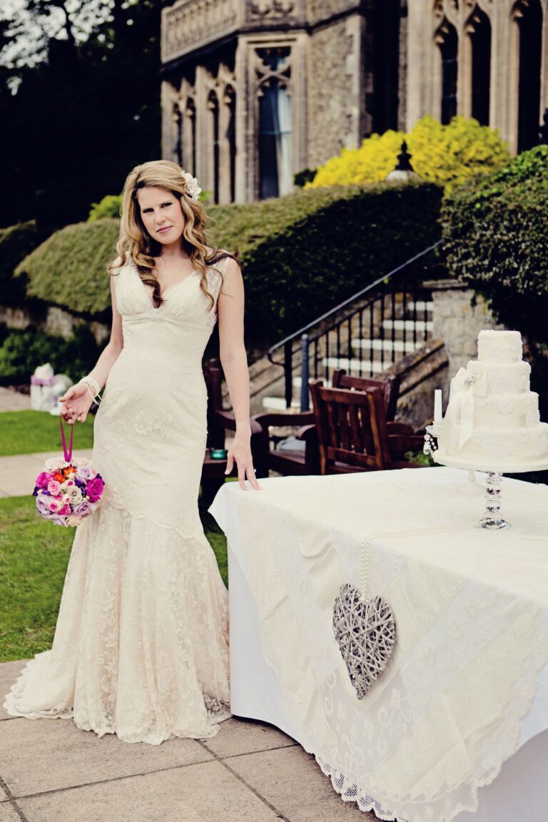 A bride in a fitted lace gown on the steps of a country house, Nadine Pyke Make Up Artist