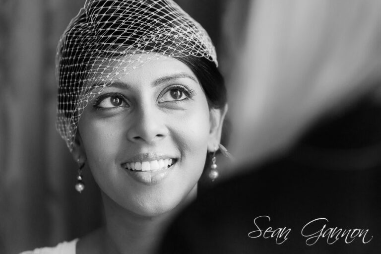 A bride in a birdcage veil, laughing (photo: Sean Gannon), Nadine Pyke Make Up Artist