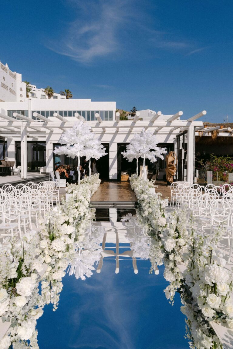 Aisle lined with white flowers leading to a pergola, Naido Wedding