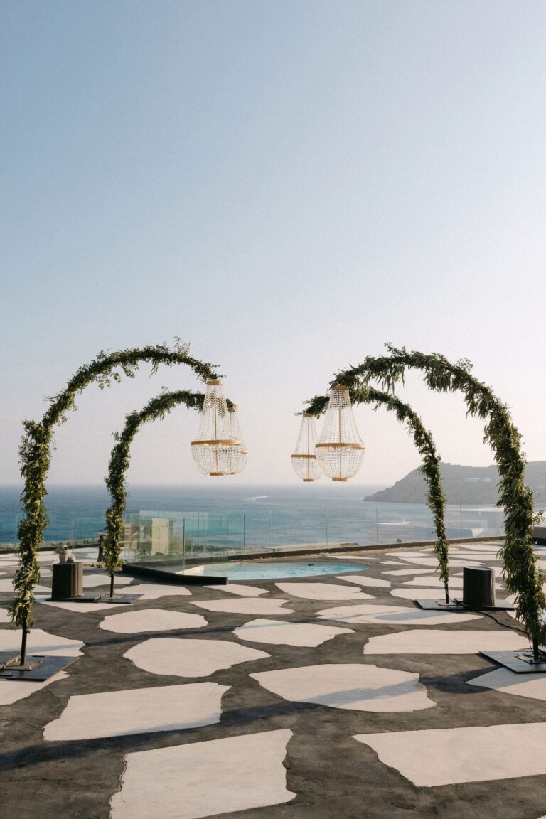 Two green floral arches on a stone terrace facing the sea, Naido Wedding