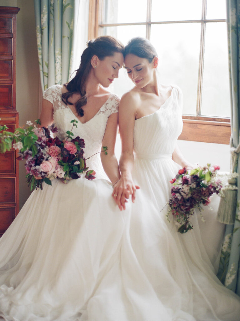 Two brides seated together in Naomi Neoh gowns, Delicately Decadent styled shoot