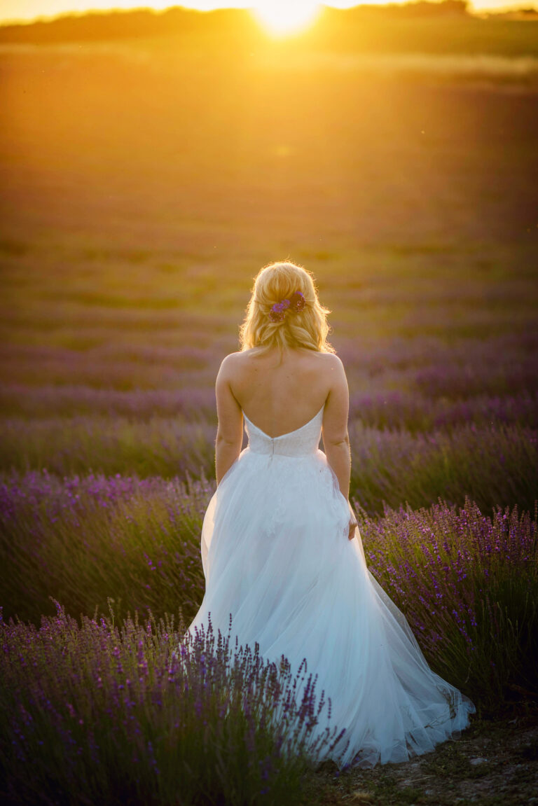A bride in a Naomi Neoh gown walking away through a lavender field at sunset, Lavender Lust styled shoot