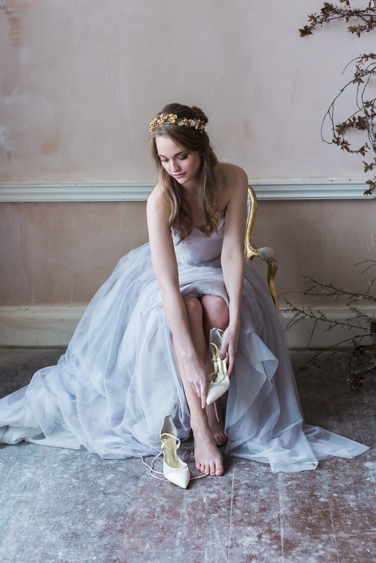 A bride in a Naomi Neoh tulle gown seated against a pink wall, The Violet Vigour styled shoot