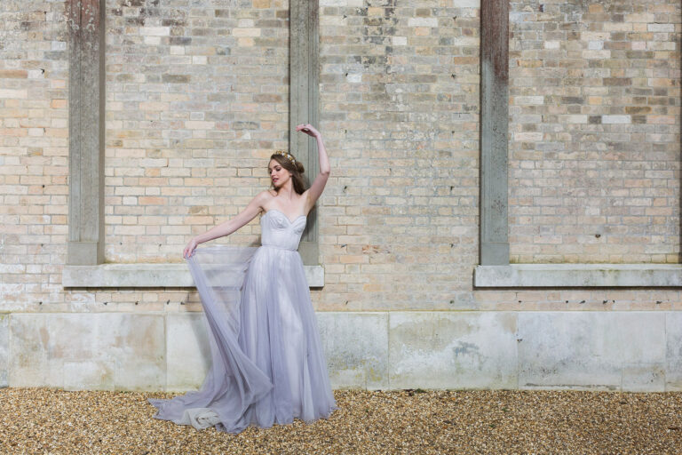 A bride in a Naomi Neoh gown against a brick wall, The Violet Vigour styled shoot