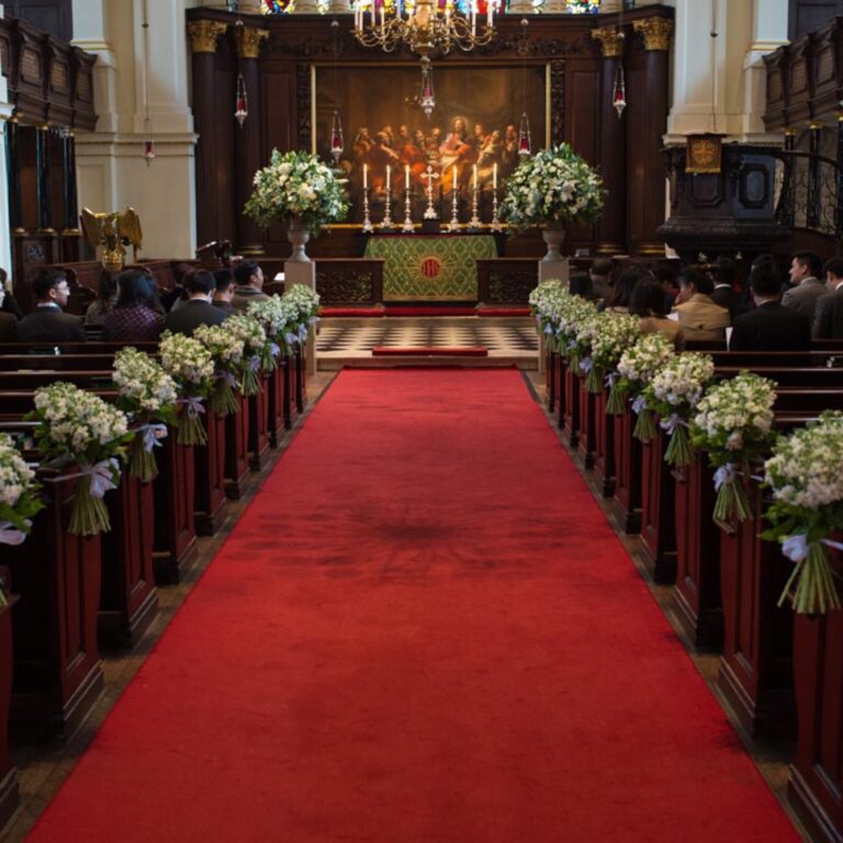 A red carpet aisle lined with flowers in a church at a Niemierko wedding