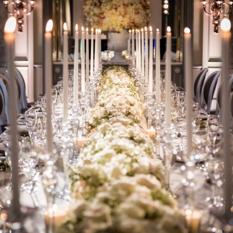 A candlelit long table with white flowers at a Niemierko wedding at The Savoy