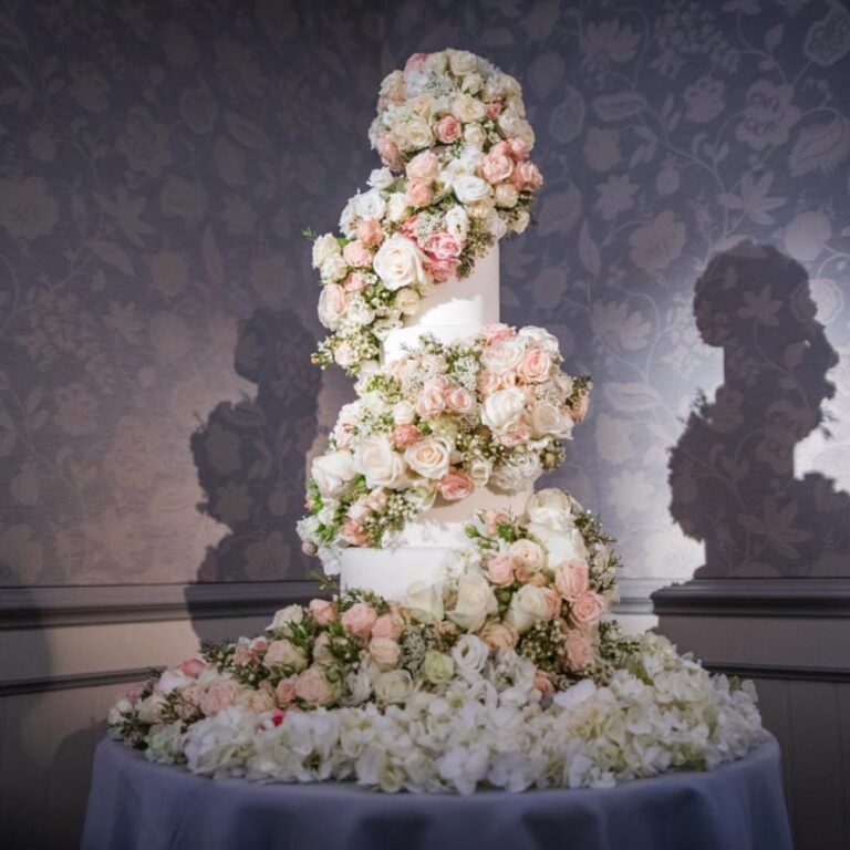 A tiered wedding cake covered in flowers at a Niemierko wedding at The Savoy