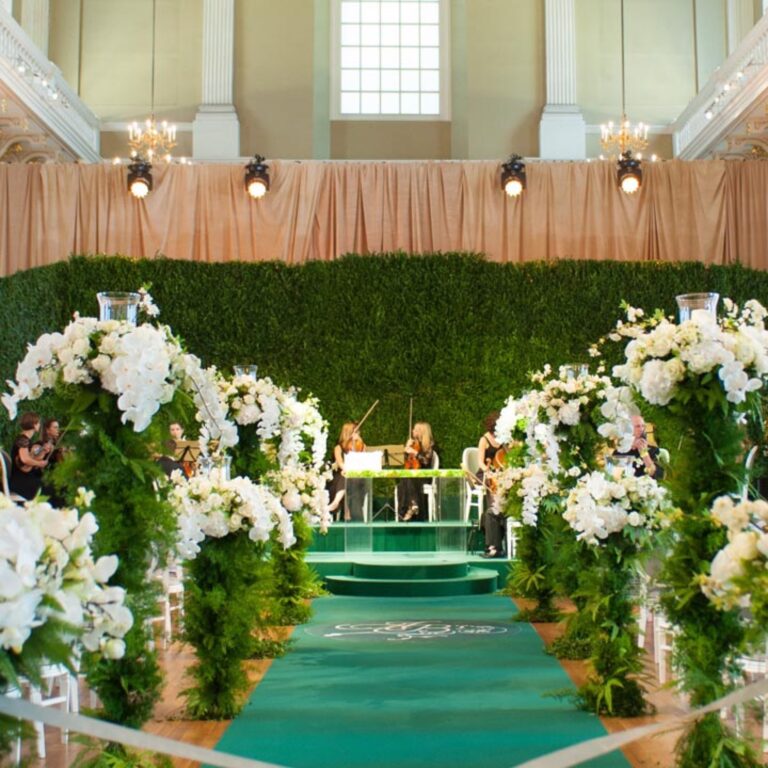 A green aisle lined with flowers at a Niemierko wedding at Banqueting House