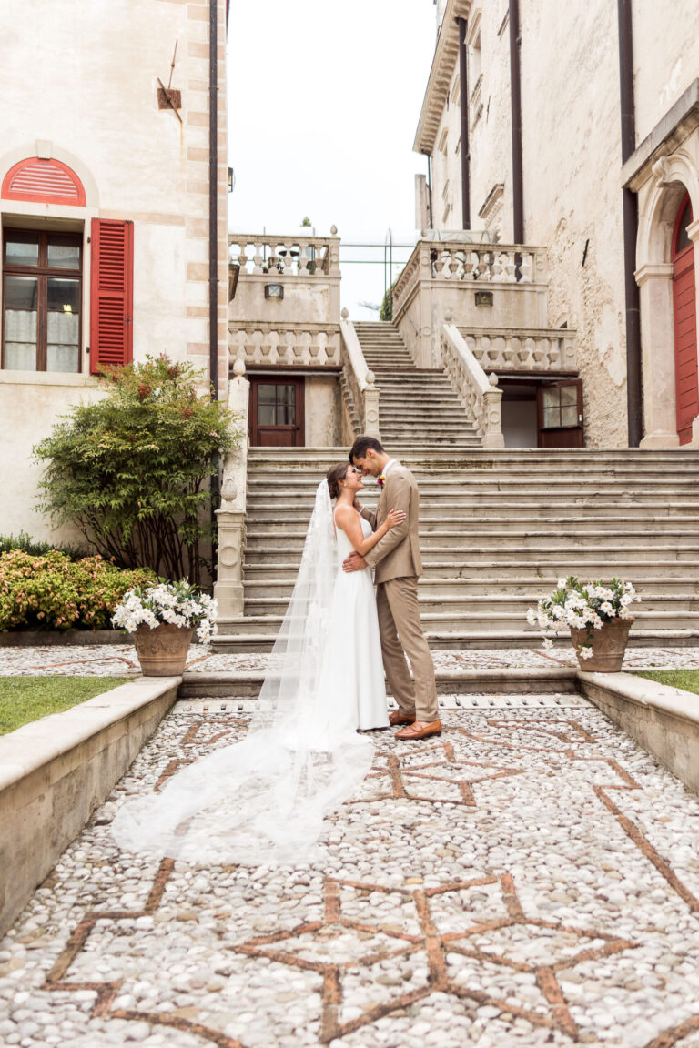 A couple at the foot of a villa's double staircase, a star mosaic in the cobbles, Noemi Wedding