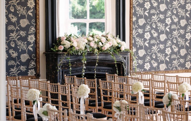 Ceremony chairs beside a fireplace dressed with flowers, Non Such Mansion