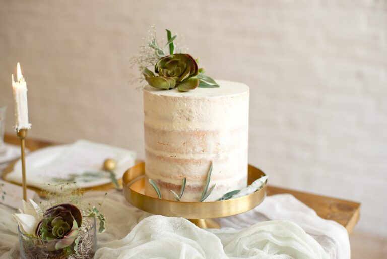 Small wedding cake with a succulent topper beside a candle, Nordic Adventure Weddings
