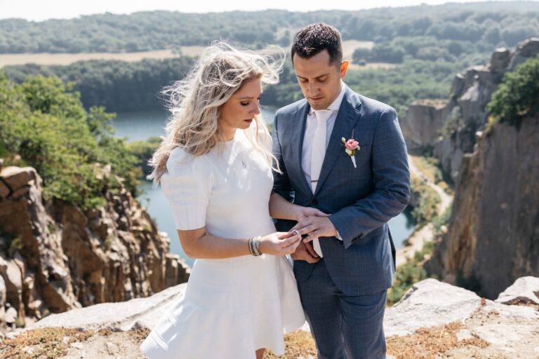 Couple exchanging rings on a clifftop overlooking a lake, Nordic Adventure Weddings