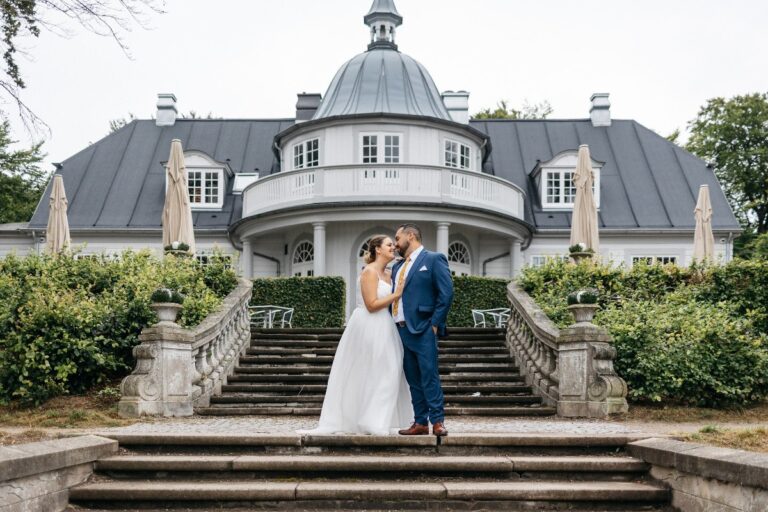 Couple on the steps of a manor with a domed pavilion, Nordic Adventure Weddings