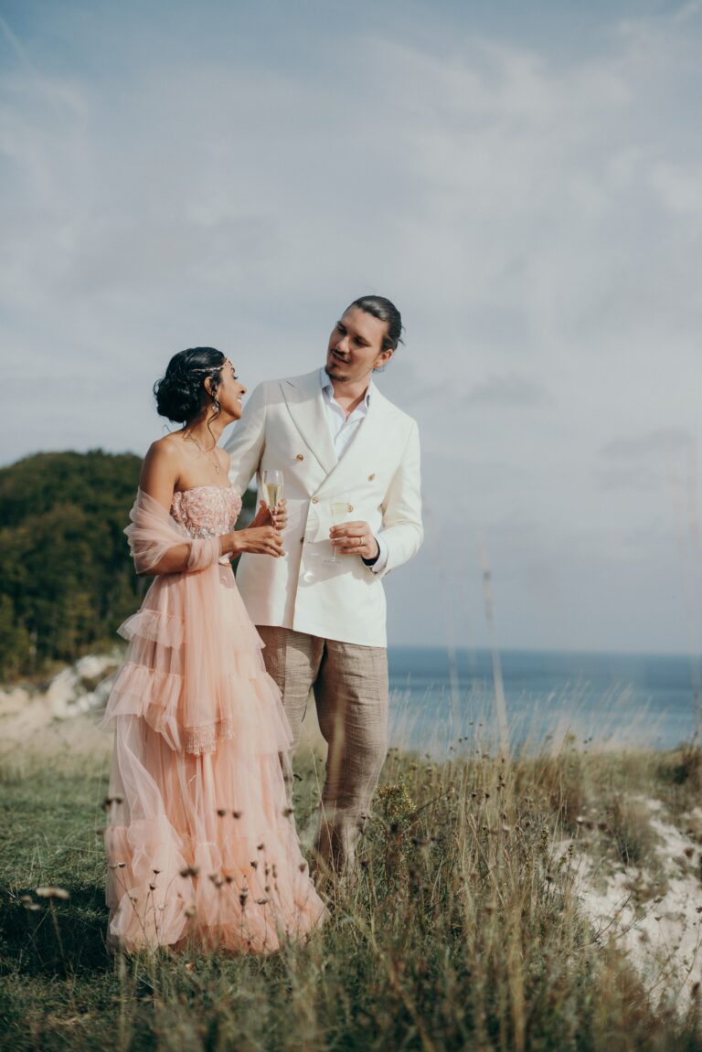 Couple on a clifftop above the sea, the bride in a pink tulle gown, Nordic Adventure Weddings