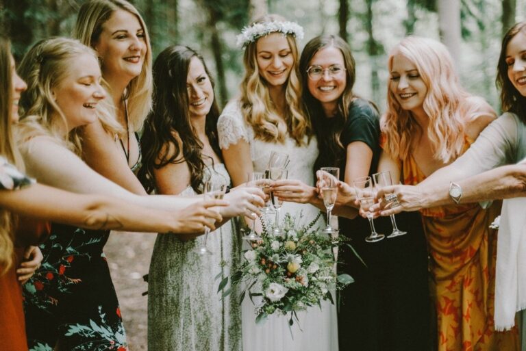 Bride and bridesmaids raising glasses in a forest, Nordic Adventure Weddings