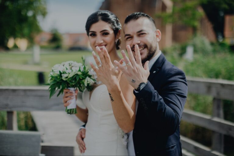 Couple showing their wedding rings, the bride holding white flowers, Nordic Adventure Weddings