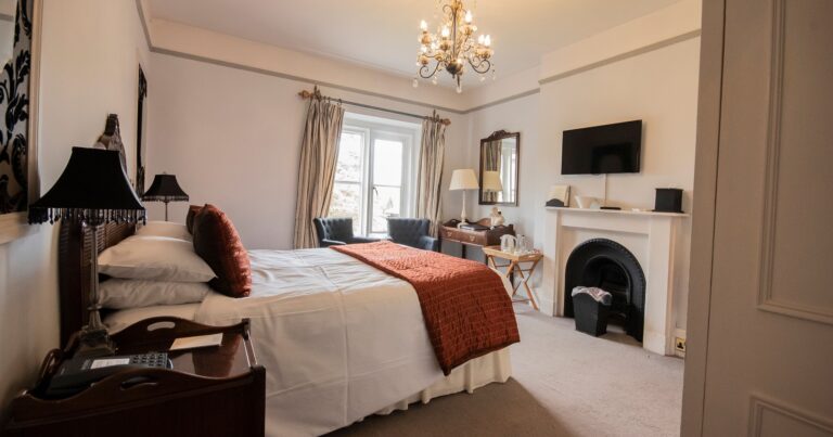 A bedroom with a cast-iron fireplace, chandelier and views from the window, Northcote Manor Hotel