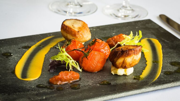 Seared scallops with roasted tomatoes and saffron sauce on slate, Northcote Manor Hotel