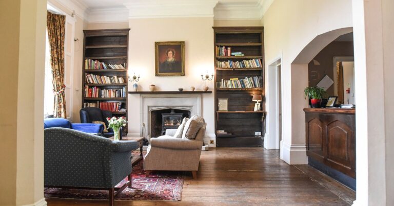A lounge with bookshelves either side of a stone fireplace and a family portrait above, Northcote Manor Hotel