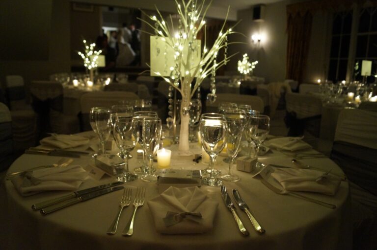 Tables lit by candles and white branch centrepieces for an evening reception, Northcote Manor Hotel