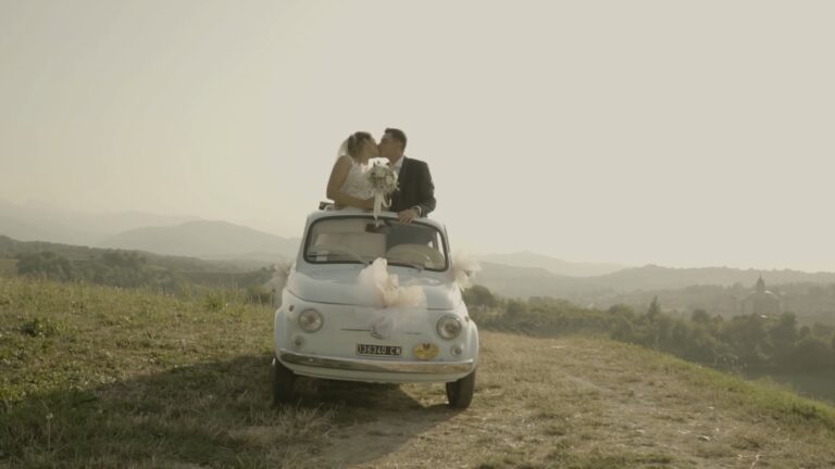 A kiss on the roof of a Fiat 500 above hazy hills, from Martina and Pietro's trailer, Nozze da film
