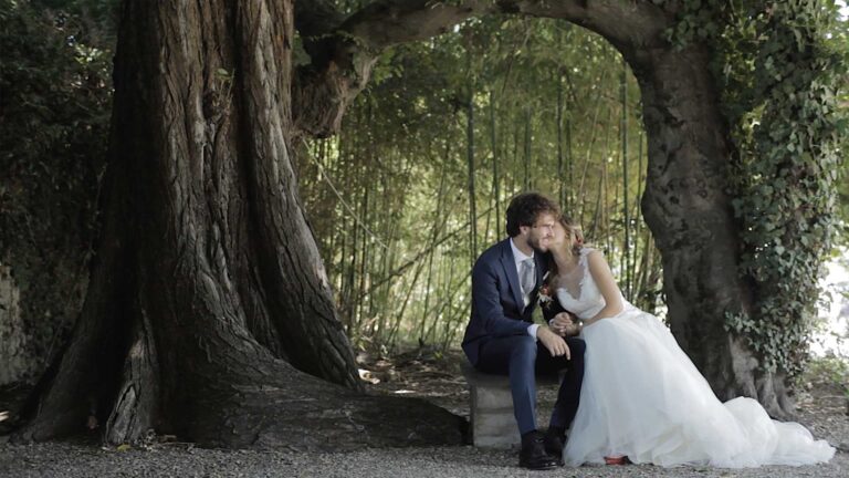 The couple seated beneath the arch of an old tree in a garden, Nozze da film