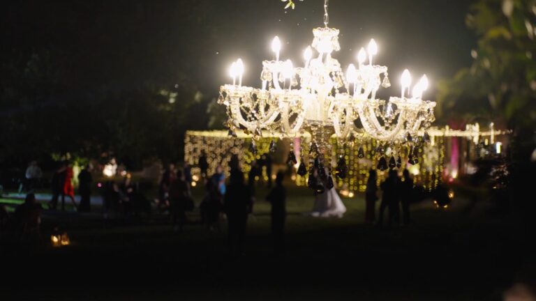 A crystal chandelier hung in the garden over an evening reception, from Jessica and Luigi's trailer, Nozze da film
