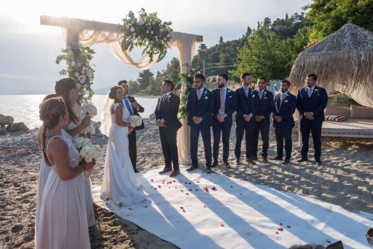 A beach ceremony with the groom's party and a floral arch, Nunta pe Plaja