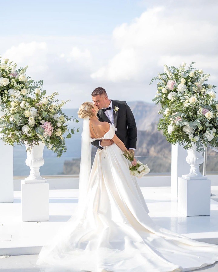 A bride and groom on a Greek terrace with floral arrangements, Nunta pe Plaja