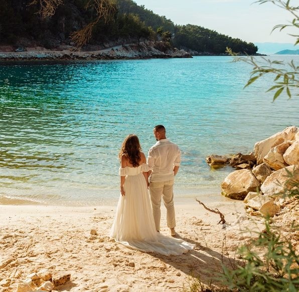 A couple on a rocky beach with turquoise water, Nunta pe Plaja