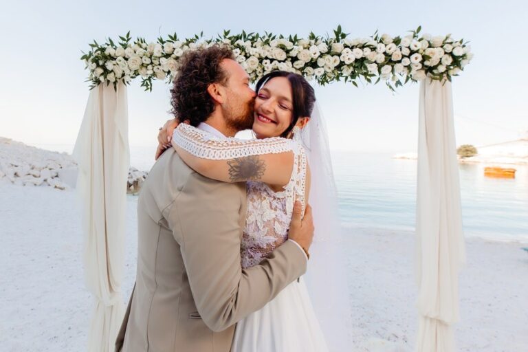 A couple embracing under a floral arch, Nunta pe Plaja