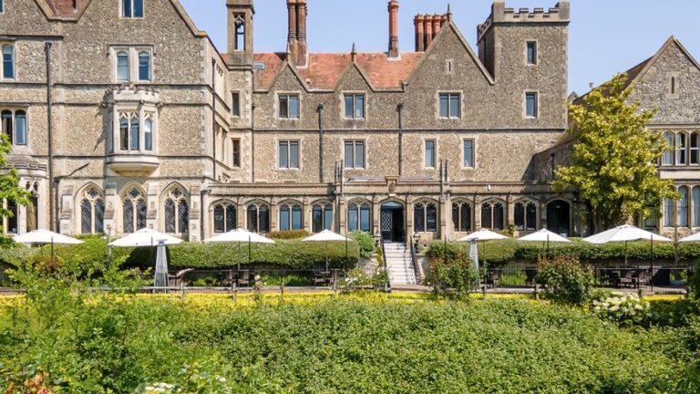 The stone facade above the south terrace, parasols set out on a summer afternoon, Nutfield Priory Hotel & Spa