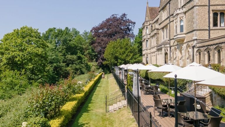The garden terrace with parasols and clipped hedges, the countryside falling away below, Nutfield Priory Hotel & Spa