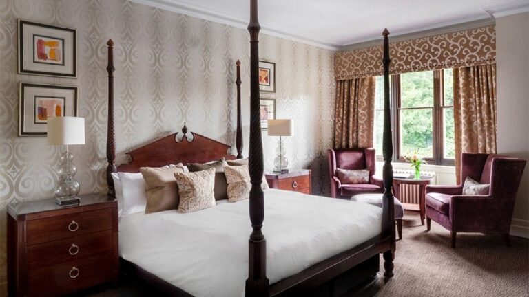 A Feature Room, a hand-carved four-poster framed by tall windows, Nutfield Priory Hotel & Spa