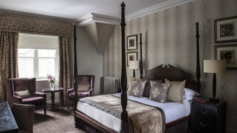 A Feature Room dressed in soft neutrals, a four-poster and armchairs by the window, Nutfield Priory Hotel & Spa