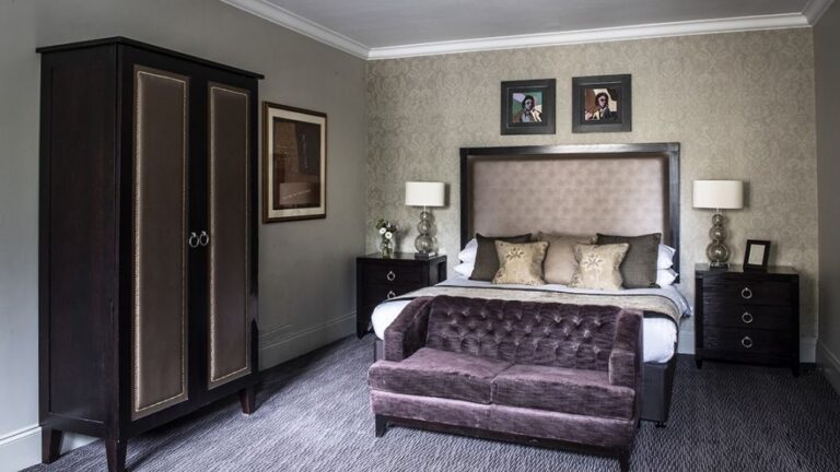 A Deluxe bedroom with a velvet headboard and its own sitting area, Nutfield Priory Hotel & Spa
