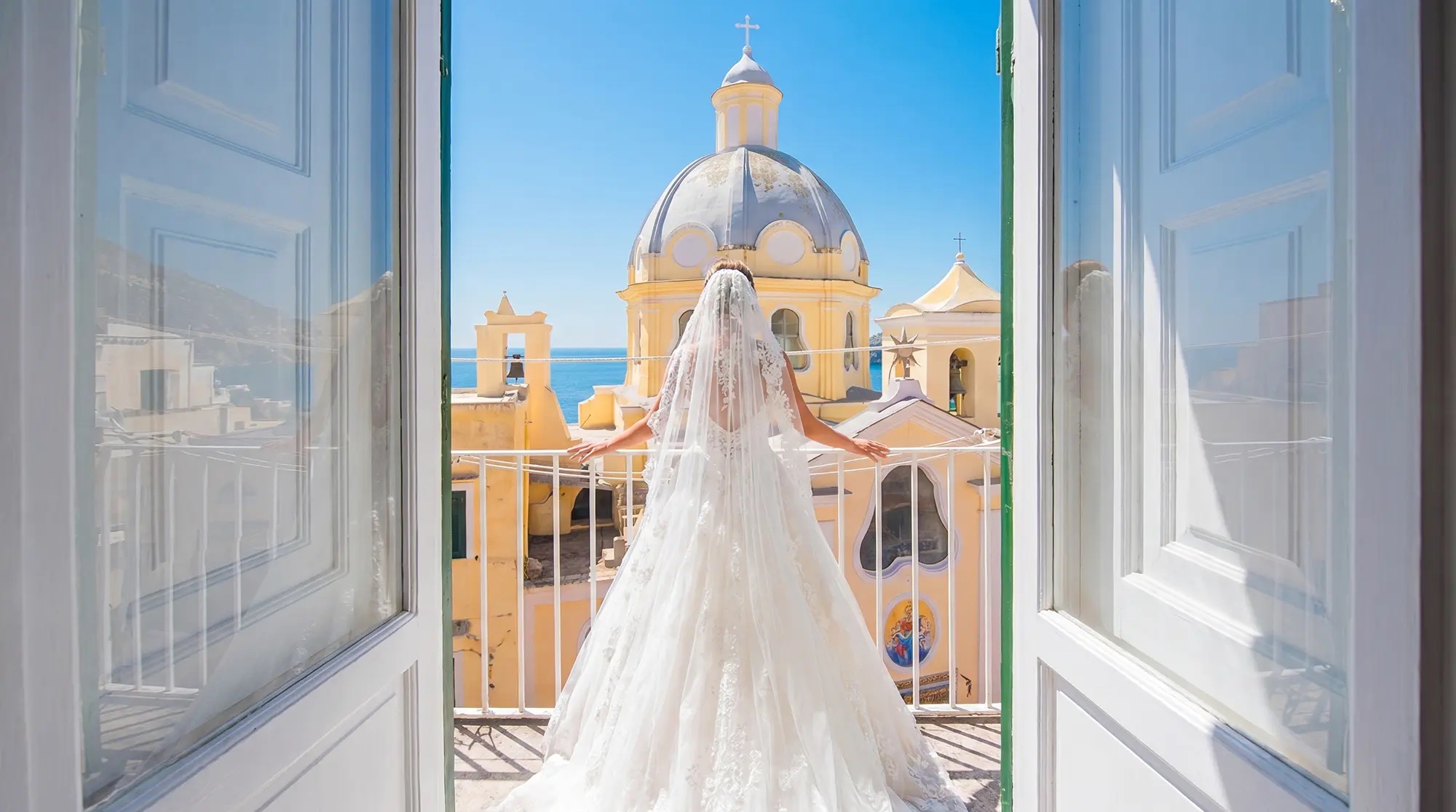 The bride at an open window, her train spread across the balcony, O'Sarracino Events