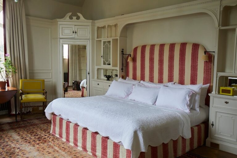 A bedroom with a striped bed and fitted joinery, Oakley Court Hotel, Windsor