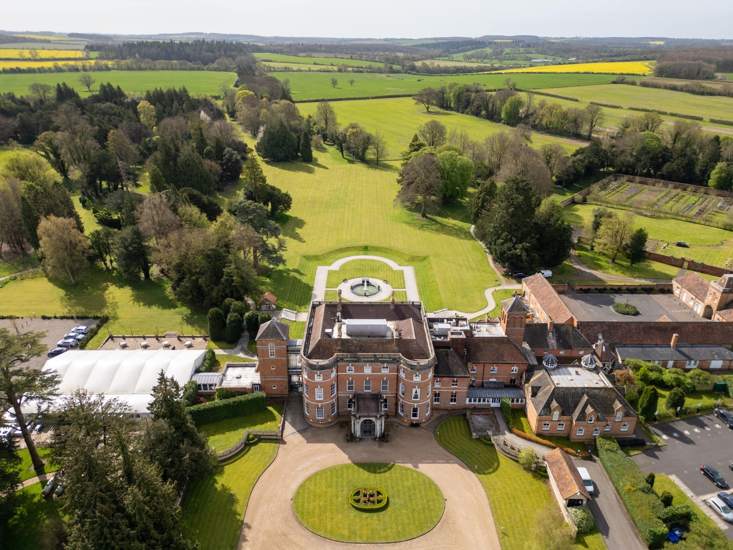 Aerial view over the turning circle and house towards the Garden Pavilion, the walled Kitchen Garden and open Hampshire farmland, Oakley Hall Hotel