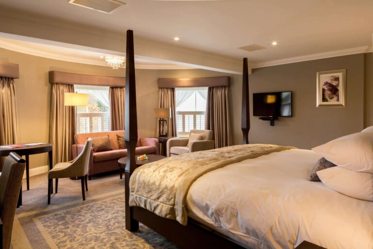 A Four Poster Suite on the top floor of the main house, with a sitting area beyond the bed, Oakley Hall Hotel