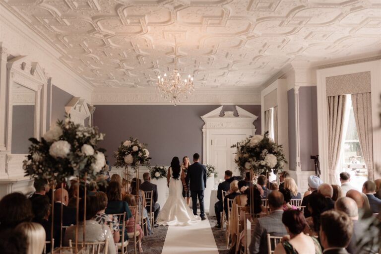 A civil ceremony in the Garden Suite rooms under an ornate plaster ceiling, guests seen from behind, Oakley Hall Hotel
