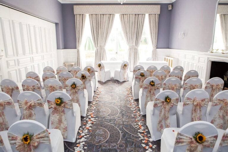The Winchester room set for a ceremony, with covered chairs and petals along the aisle, Oakley Hall Hotel