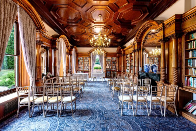 The Library set for a small ceremony, with carved wood panelling, a coffered ceiling and bookcases, Oakley Hall Hotel
