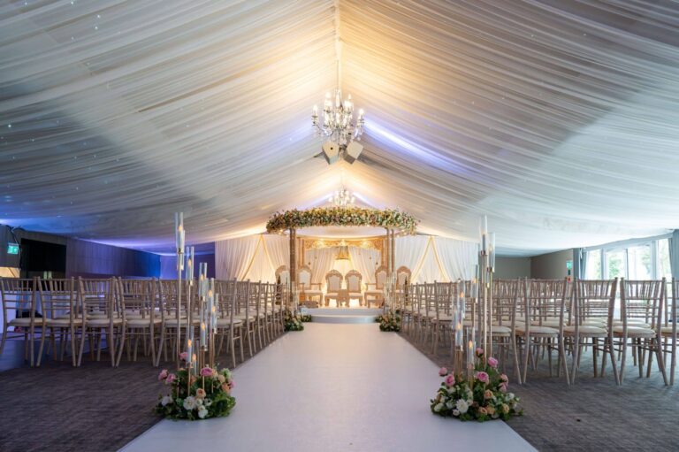 A mandap staged at the end of a white aisle in the Garden Pavilion for a Hindu ceremony, Oakley Hall Hotel